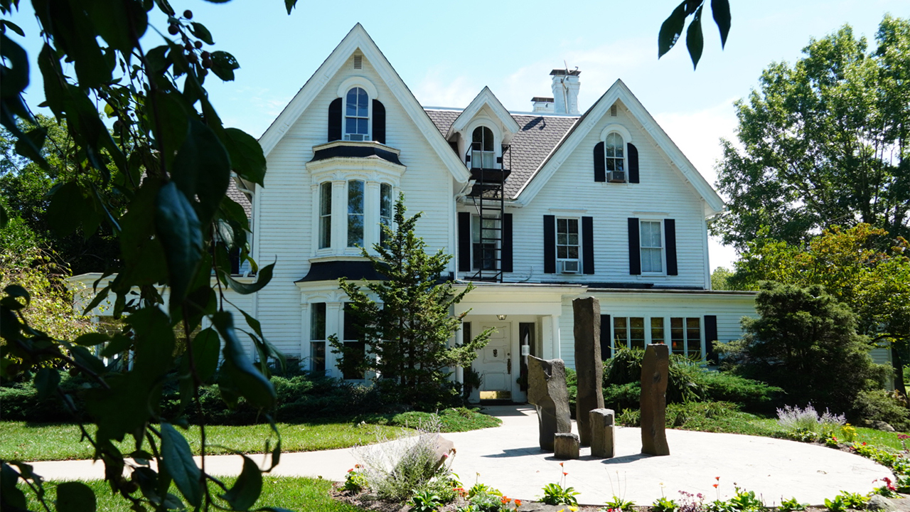 A large white house with a lawn and trees